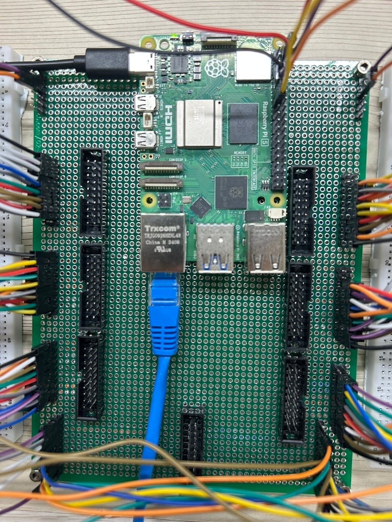 양쪽 출력판의 배선이 들어오는 중앙판에 Raspberry Pi 5와 일곱 개 IDC 헤더를 조립한 모습.